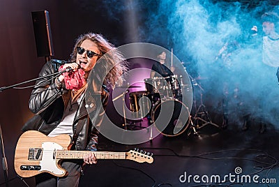 Male singer with microphone and rock and roll band performing hard rock music Stock Photo