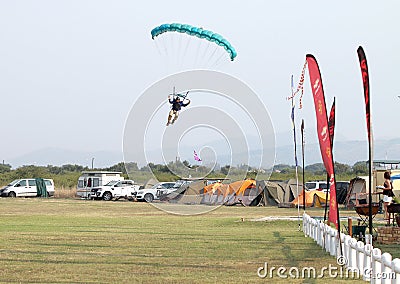 Male skydiver coming in for landing on grass with open brightly Editorial Stock Photo