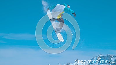 Male snowboarder flies through the air and does a spinning nose grab Stock Photo