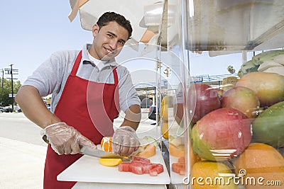 Male Street Vendor Chopping Fruits Stock Photo