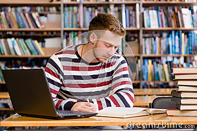 Male student with laptop studying in the university library Stock Photo