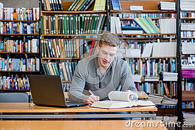 Male student with laptop studying in the university library Stock Photo