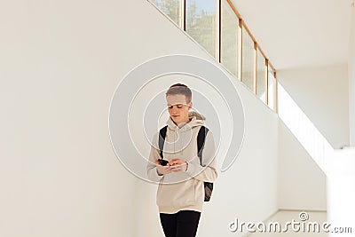 Male student walking in university corridor. Young man with smartphone in college Stock Photo