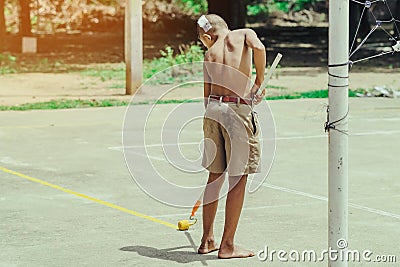 Male students use small paint rollers to paint yellow lines on the cement floor for Sepak Takraw Editorial Stock Photo