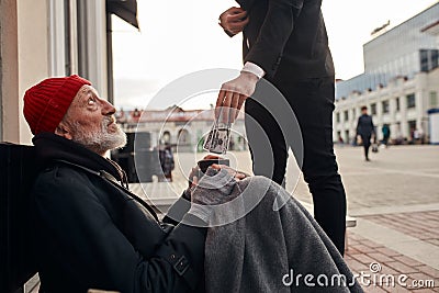 Unrecognizable man in tuxedo give money donation to homeless Stock Photo