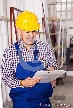 Male surveyor in coverall doing checkup and filling papers Stock Photo