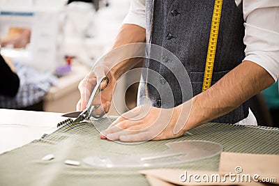 Male Tailor Cutting Fabric Stock Photo