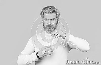 Male taking a pill with a glass of water. Man take some pills, holds glass of water, isolated on blue. Black and white Stock Photo