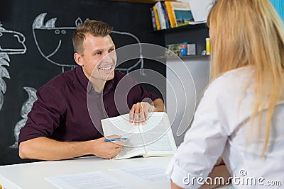 Male teacher and female parent having a discussion in classroom. Mom at teacher parent meeting at kindergarten Stock Photo