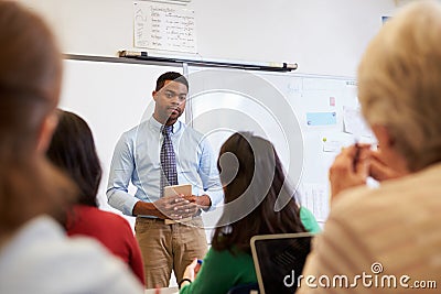 Male teacher listening to students at adult education class Stock Photo