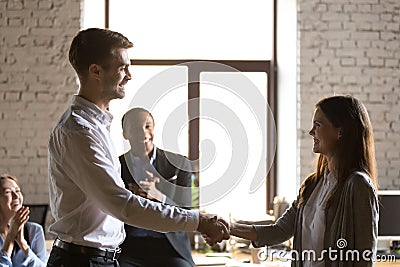 Male team leader handshaking female excited employee congratulat Stock Photo