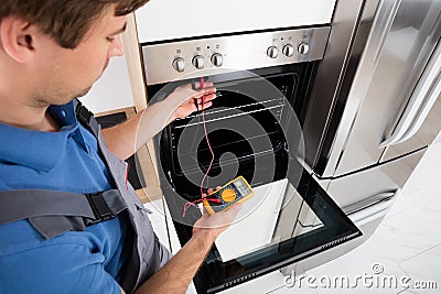 Male Technician Checking Oven Stock Photo