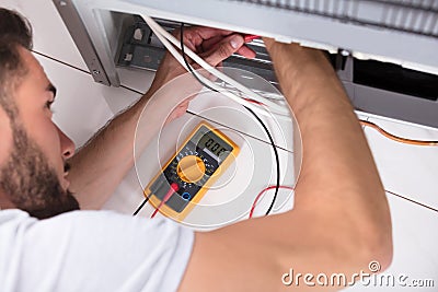 Male Technician Examining Refrigerator Stock Photo