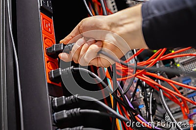 Male Technician insert Power Cable in Outlet in Datacenter Stock Photo