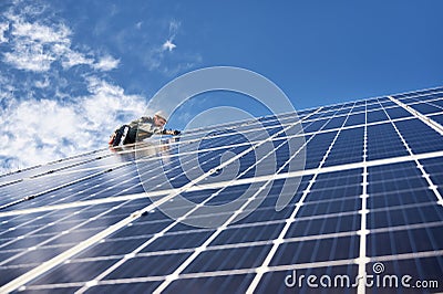 Man electrician installing solar panel under blue sky. Stock Photo
