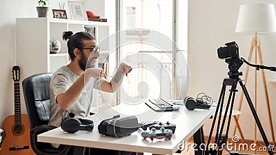 Male technology blogger pointing down, asking followers to subcribe, recording video blog or vlog about new gadgets at Stock Photo