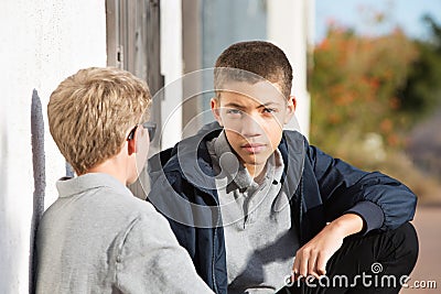 Male teen with serious expression listening to friend Stock Photo