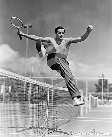 Male tennis player jumping over net Stock Photo