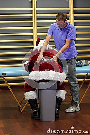 male therapist massaging overworked Santa Claus Stock Photo