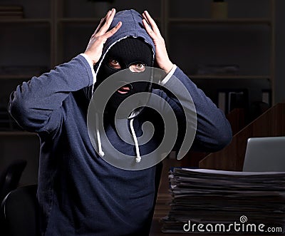 Male thief in balaclava in the office night time Stock Photo