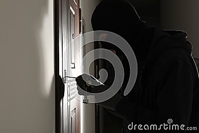 Male thief opening door with keys indoors Stock Photo