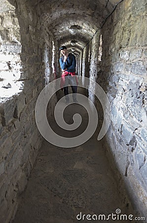 Male tourist in a narrow tunnel of stone walls of an old fortress Stock Photo