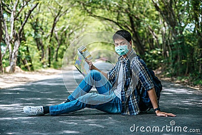 Male tourists sit and look at the map on the road Stock Photo