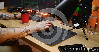 Male trader uses computer mouse, types on keyboard, analyzes real-time stocks Stock Photo