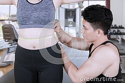 Male trainer measuring slim waist of his client Stock Photo