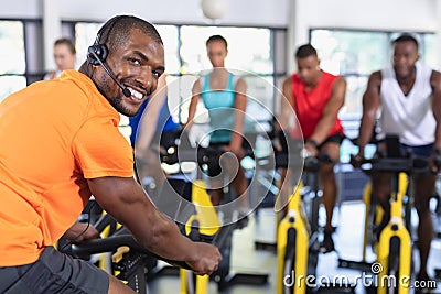 Male trainer training people to work out on exercise bike Stock Photo