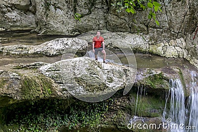 A male traveler admires waterfalls on the Agura River in Sochi Stock Photo