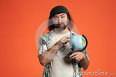A male traveler is holding a globe, a map of the world, choosing where to go. Disgruntled man points to a place on the Stock Photo