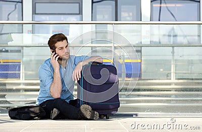 Male traveler sitting on floor talking on mobile phone Stock Photo