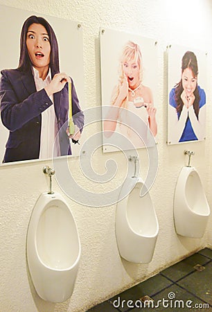 Male Urinals with poster of ladies looking Editorial Stock Photo