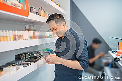 male vape seller looking at his phone while standing Stock Photo