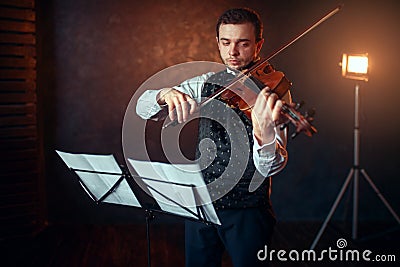 Male violinist with violin against music stand Stock Photo