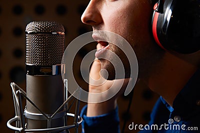 Male Vocalist Singing Into Microphone In Recording Studio Stock Photo