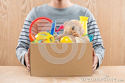 Male volunteer holding donation box with old toys. Stock Photo