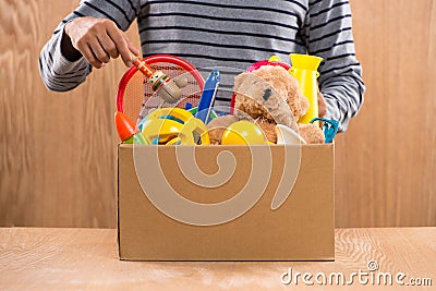 Male volunteer holding donation box with old toys. Stock Photo