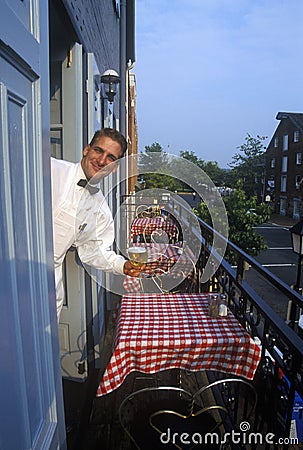 Male waiter outside red-checked tables at outdoor Fish Market restaurant in Alexandria, VA Editorial Stock Photo