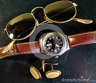 Male watch, cuff buttons and sunglasses on the leather top desk Stock Photo