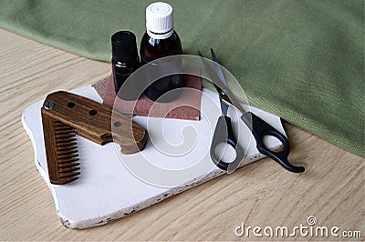 Male wooden comb, care oils and scissors for haircuts on white desk Stock Photo