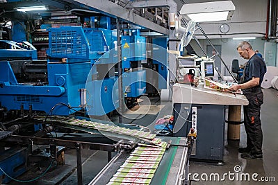 Male worker controlling printing machine Editorial Stock Photo