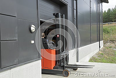 Male worker driving out of a warehouse on the fork-lift-truck Editorial Stock Photo