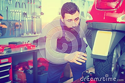 Male worker fixing failed scooter in workshop Stock Photo