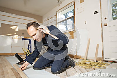 A Male Worker install wood floor on a house Stock Photo