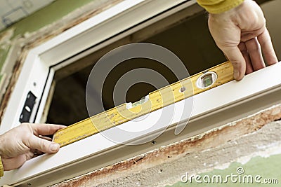 The male worker installs UPVS the window using the level. Stock Photo