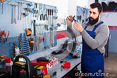Male Worker is observing motorbike part for fixing Stock Photo