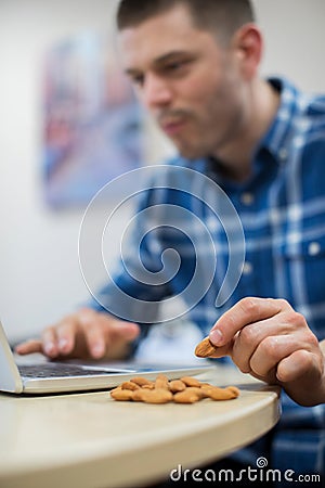 Male Worker In Office Having Healthy Snack Of Nuts Stock Photo