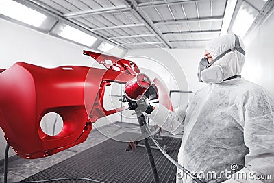 Male worker in protective clothes and mask painting car using spray paint. Stock Photo